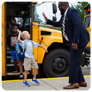 Assistant Principal Mr. Little High-fives a student coming off the school bus