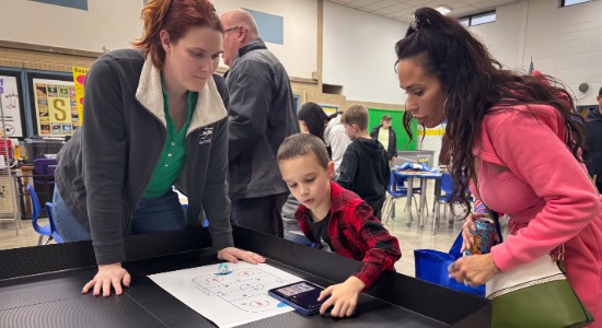 Woman guilds little boy in using the Ozobot robots