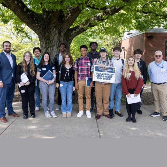   Group of students pose with senator and their teacher in front of a large tree