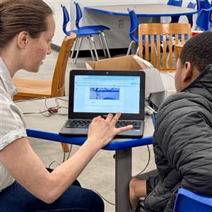 Mentor works with student on laptop