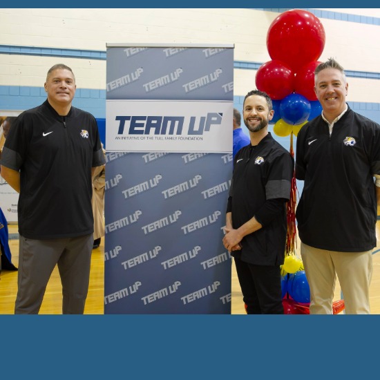  Coach Loya, Superintendent DiLucente, and Principal Long pose in front of TeamUp banner